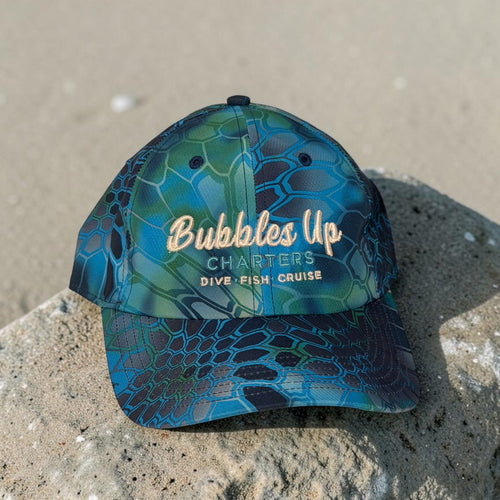 Blue and green cap with 'Bubbles Up Charters' text on a stone surface
